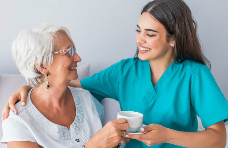caregiver giving an elder woman a tea
